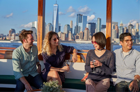 Friends sitting in the main salon of the yacht Kingston with the NYC Skyline in the background