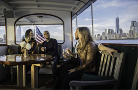 Group of friends sitting at a table in the back salon of the Yacht Full with the city in the background