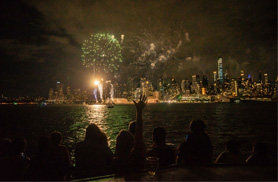 People on the bow of a yacht watching the PRIDE fireworks display in NY Harbor