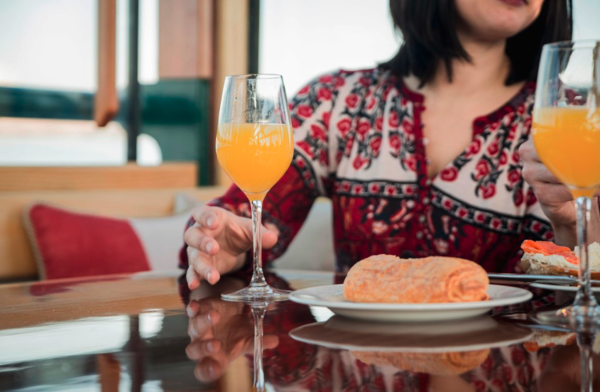closeup of a woman reaching for a glass of mimosa