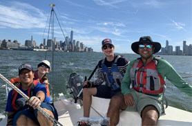 group of four people on a sailboat, smiling for a photo