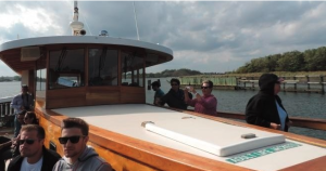 Group of guests sitting on the bow of Yacht Manhattan on a tour through the waterways of Freshkills park