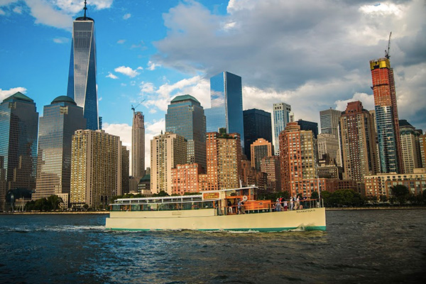 the yacht manhattan, cruising down a river with the city in the background