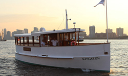 the yacht kingston cruising down a river with a landscape of the city in the background