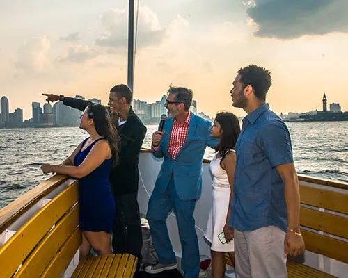 Tour guide talking to guests on the bow of a boat and pointing out to the skyline