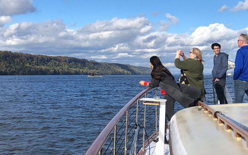 Bow of yacht Full Moon cruising up the Hudson River for a Fall Foliage cruise with the Grand Palisades in the background