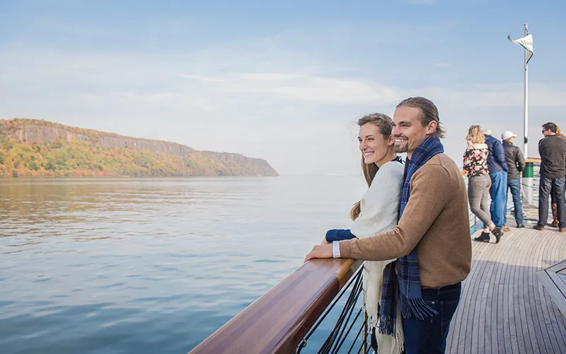 Couple on the bow of a boat with the Grand Palisades in the background