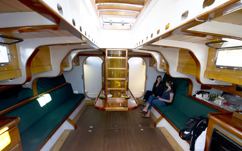an interior view of the schooner america 2.0, with two passengers talking and sitting inside