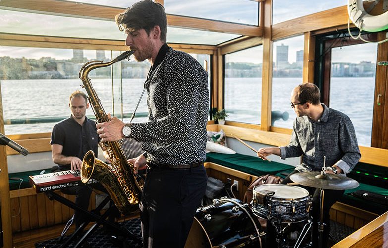 Live band playing holiday music on Yacht Manhattan II with a city landscape in the background