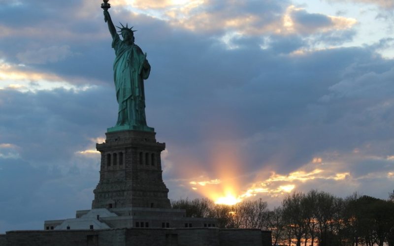 a closeup view of the statue of liberty, with a sunset behind it