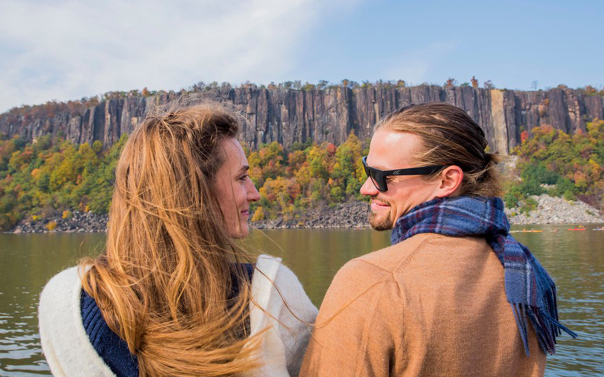 Couple looks lovingly at each other while cruising up the Hudson seeing beautiful fall foliage