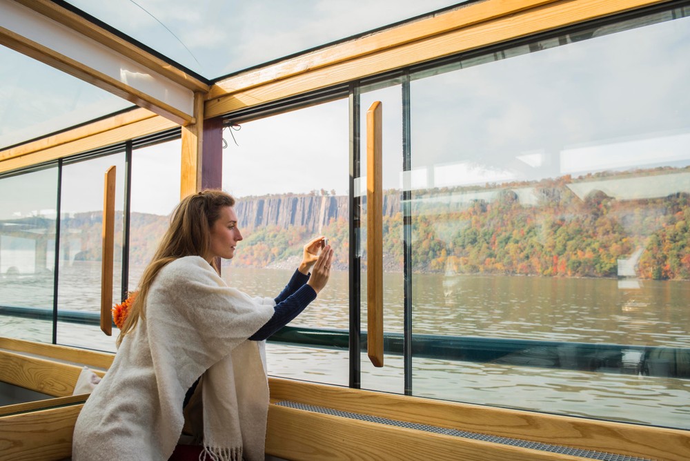 Guest takes photos of beautiful fall foliage through windows on yacht Manhattan