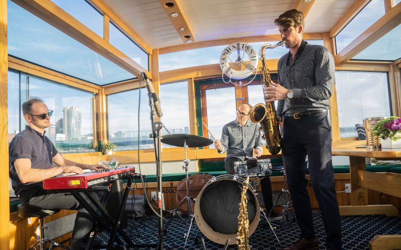 a three man jazz band playing music in the back of a classic yacht