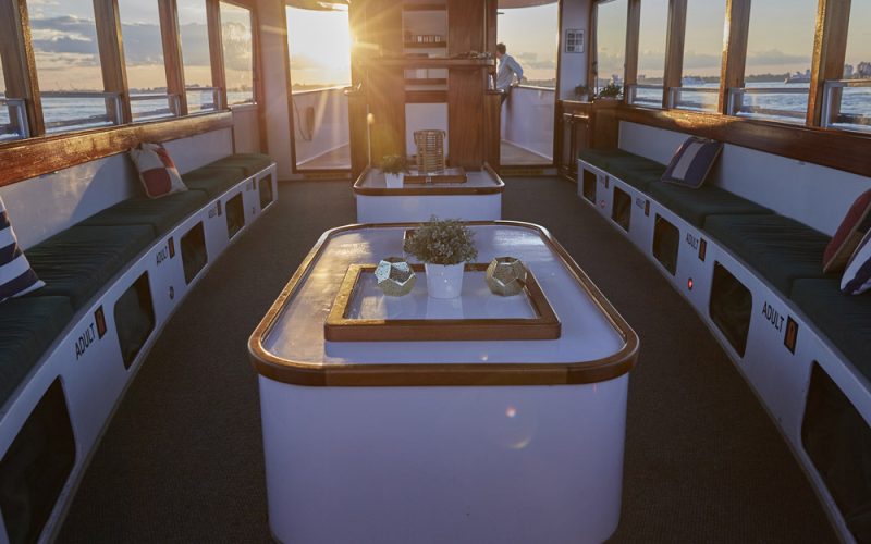 Main table that is centered in the main salon of the Yacht Kingston with the sunset showing through the windows and doors