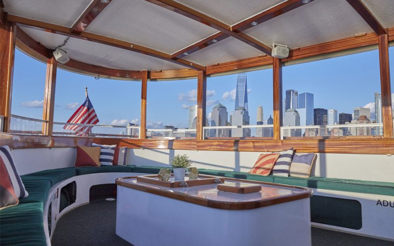 The interior salon of Yacht Kingston with the NYC Skyline seen through the back windows