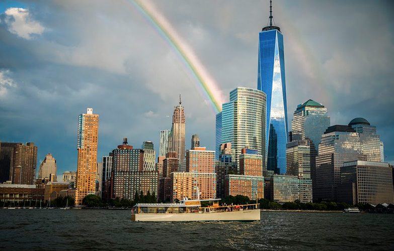 The Yacht Manhattan II Cruising through NY Harbor with a rainbow behind the NYC Skyline and World Trade Center