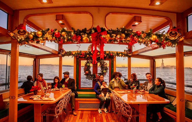 Small gathering sitting in the back of Yacht Manhattan II decorated in Holiday Decor for a Cocoa and Carols Cruise