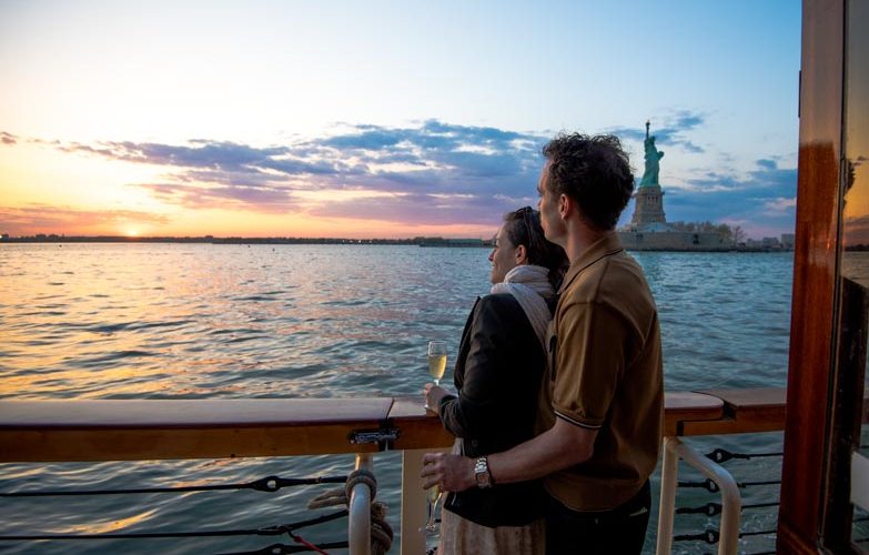 Couple aboard the bow of the Yacht Kingston looking out at the NYC Skyline