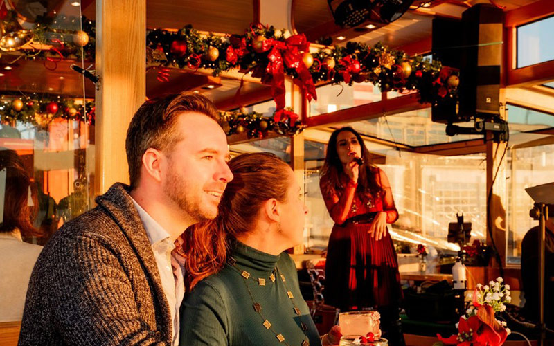 Couple listening to live holiday music on Yacht Manhattan II inside with holiday decor