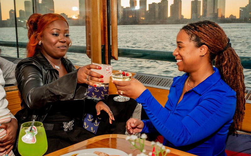 two women cheering with drinks in their hands, aboard the yacht manhattan