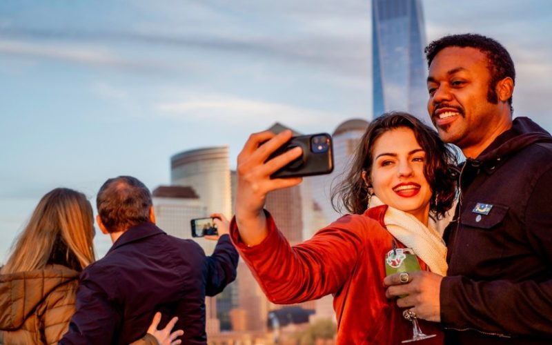 two couples, taking a selfie, with a city landscape in the background