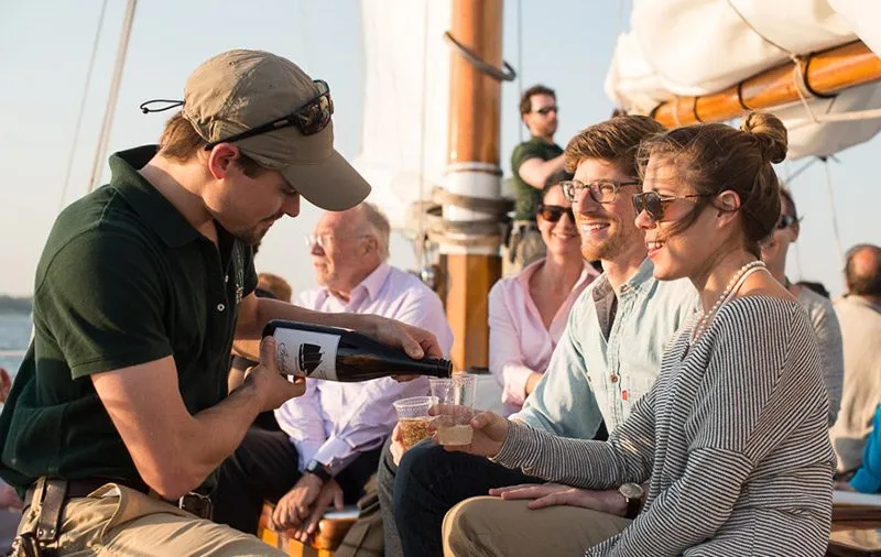Couple getting served Champagne by a crew member aboard the Schooner Adirondack
