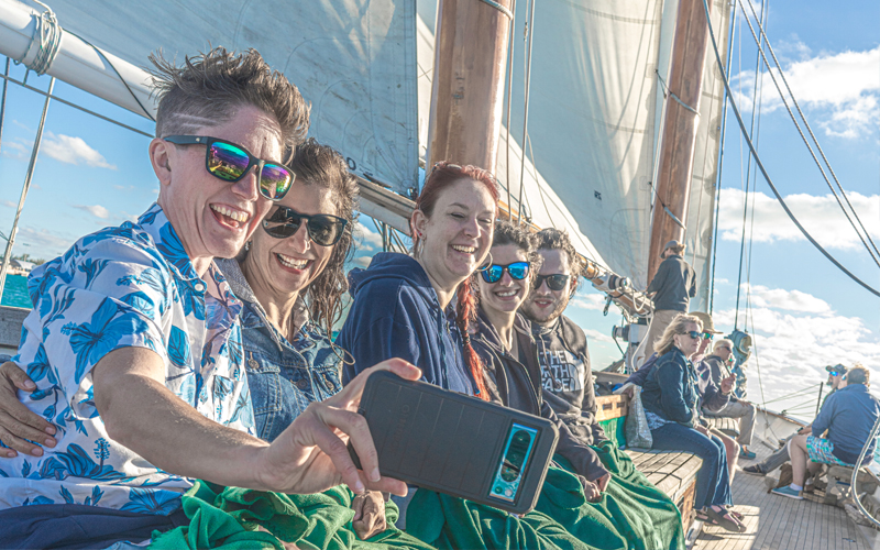 Group of guests taking a selfie on the decks of Schooner America 2.0 while sailing in NY Harbor