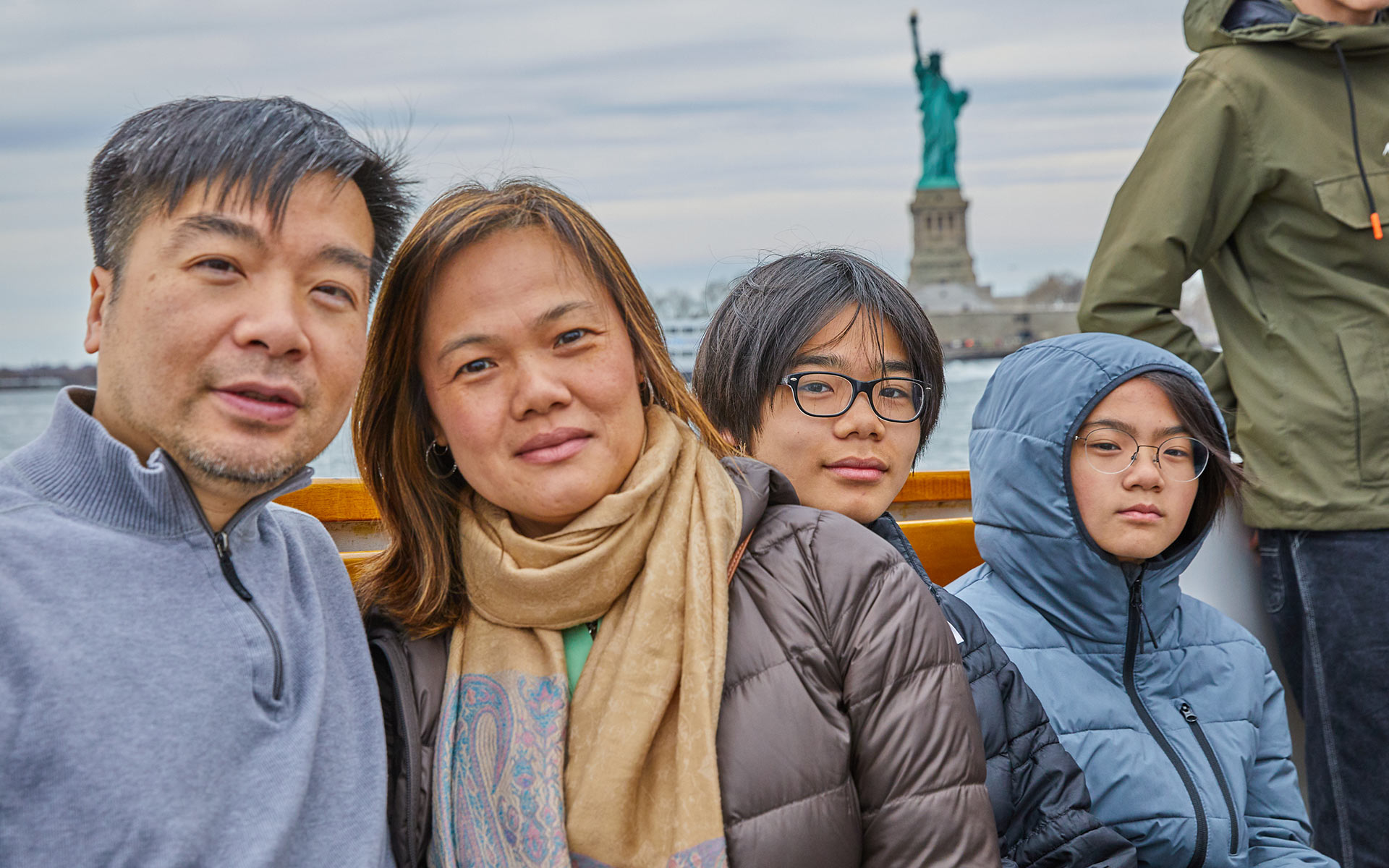 SailNYC_Mini-Yachts_Hero Family on the bow of a boat with the statue of liberty in the background