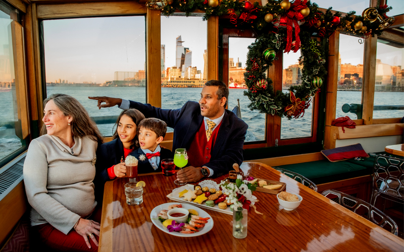 Family sitting in the main salon of the classic yacht Manhattan with Holiday decor surrounding them for a holiday sightseeing cruise