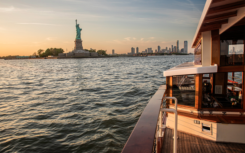 Deck of a classic yacht with the Statue of Liberty in the background