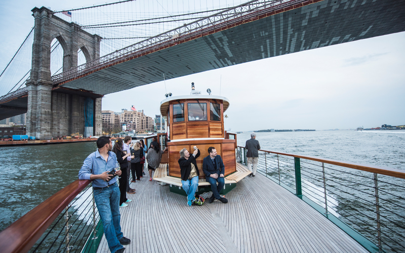 Guests on the deck of Yacht Manhattan looking up at the Brooklyn Bridge