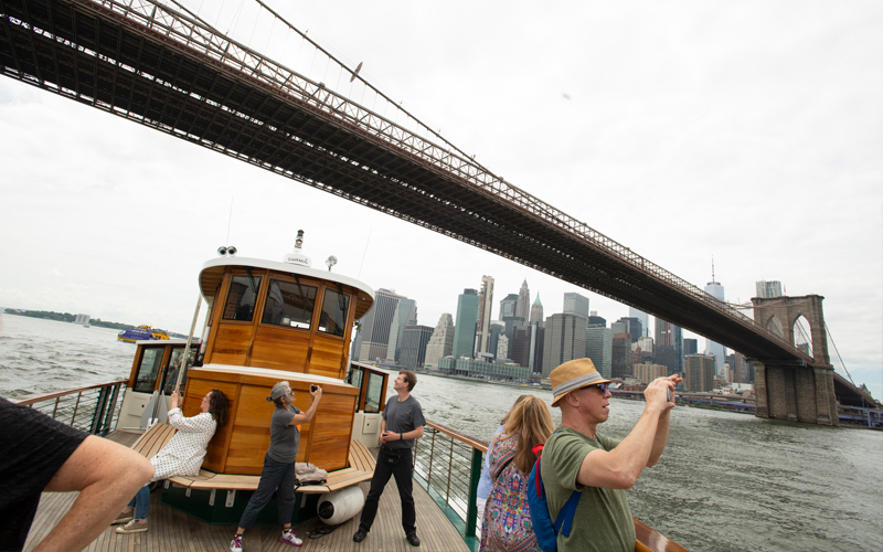 Guests on the bow of yacht Manhattan taking photos of the Brooklyn Bridge