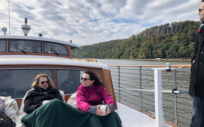 Guests on the bow of yacht Full Moon with the Grand Palisades in the background for a Fall Foliage Cruise up the Hudson River