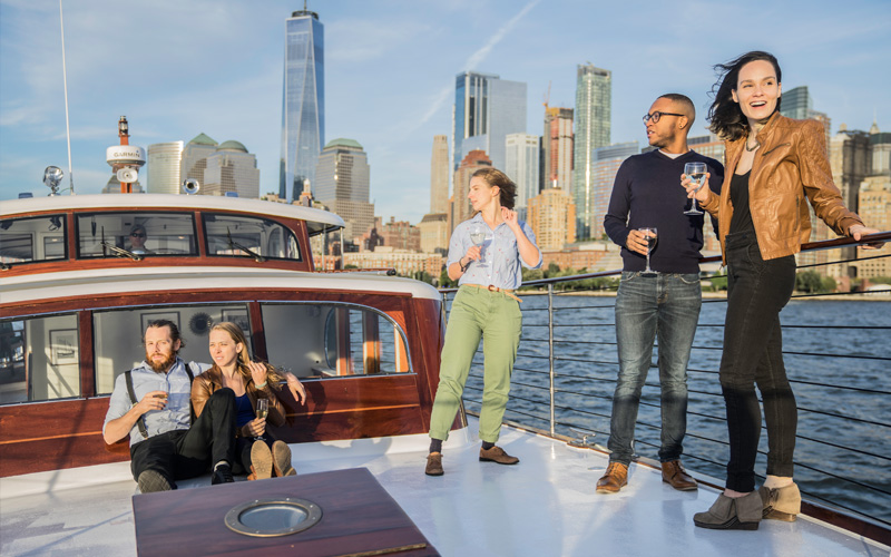 Guests on the bow of the yacht Full Moon with the NYC Skyline in the background
