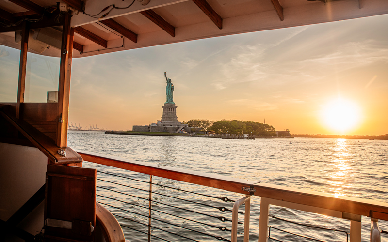 Deck of classic yacht Manhattan with the Statue of Liberty at Sunset