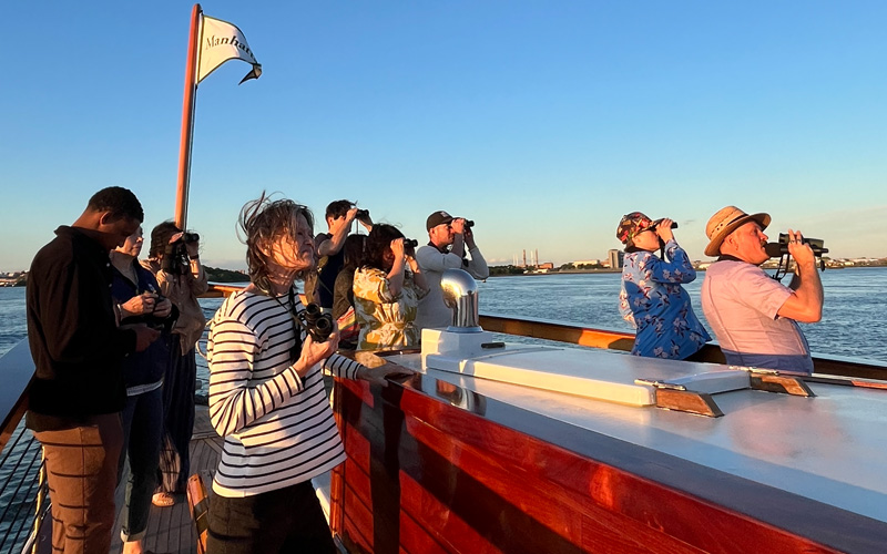 Guests on the bow of a boat looking out on a Bird watching cruise in NYC