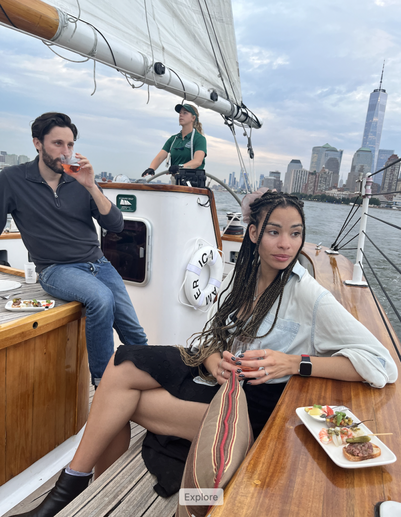 Aboard Classic Harbor Line's schooner America 2.0, couple enjoys drinks and Marea at Sea menu while being sailed down the Hudson past FIDI
