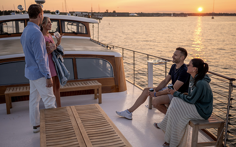 Couple on the bow of yacht Full Moon with the sun setting in the background.