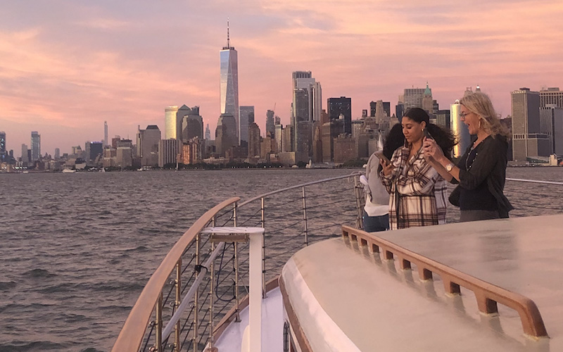 Friends on the bow of Yacht Full Moon with the NYC Skyline in the background.