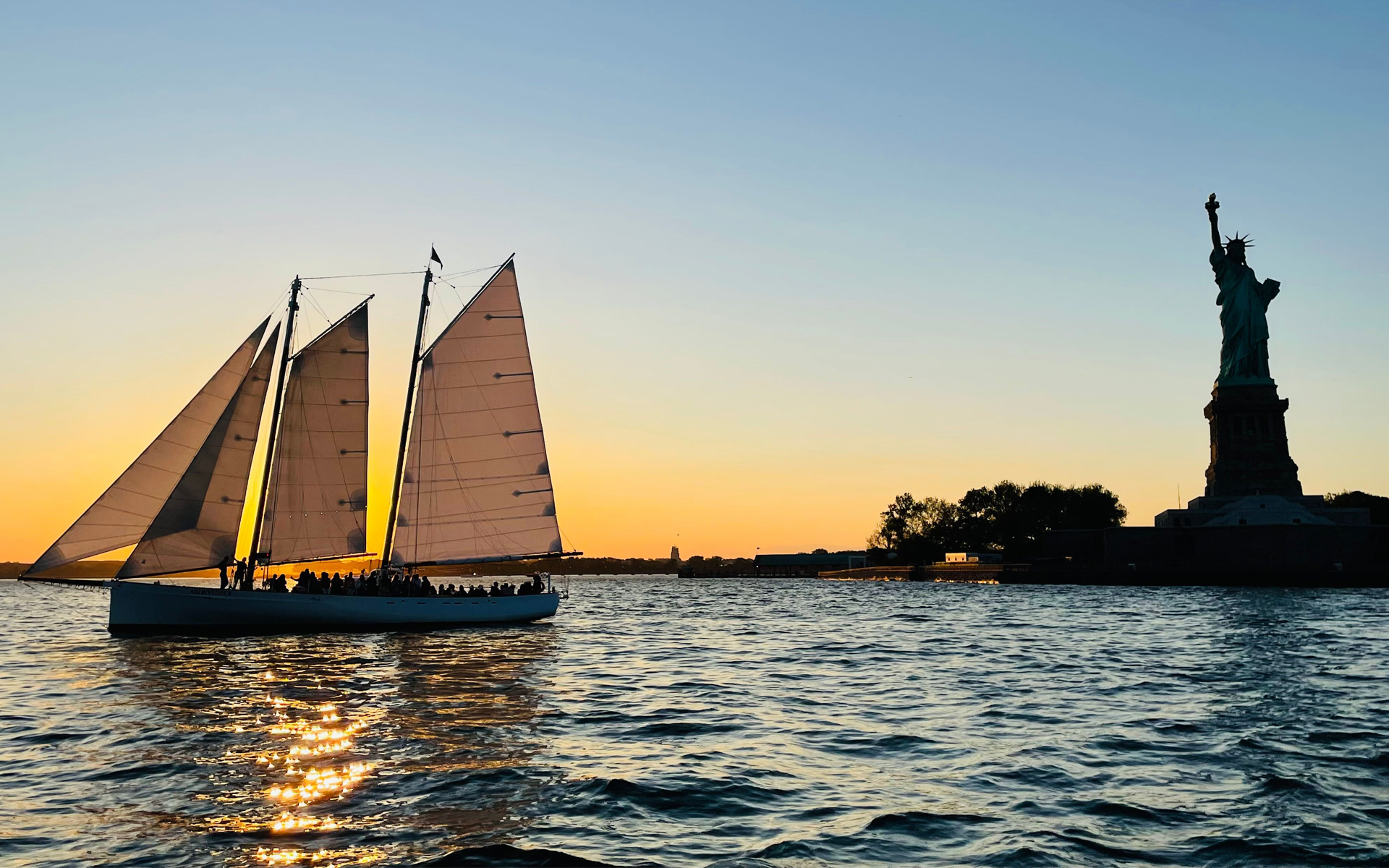 Schooner Adirondack sailing in front of the Statue of Liberty