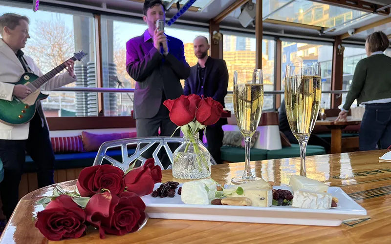 Serenade9 Two Champagne Glasses with artisanal cheese with a band playing in the background on a boat in NY Harbor