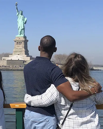 Couple on the bow of Manhattan II taking a picture of the Statue of Liberty