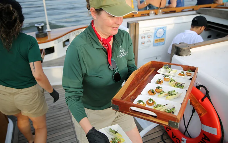 Tapas9 Crew member with a plate of fresh hors d oeuvres for the tides and tapas sail in NY Harbor