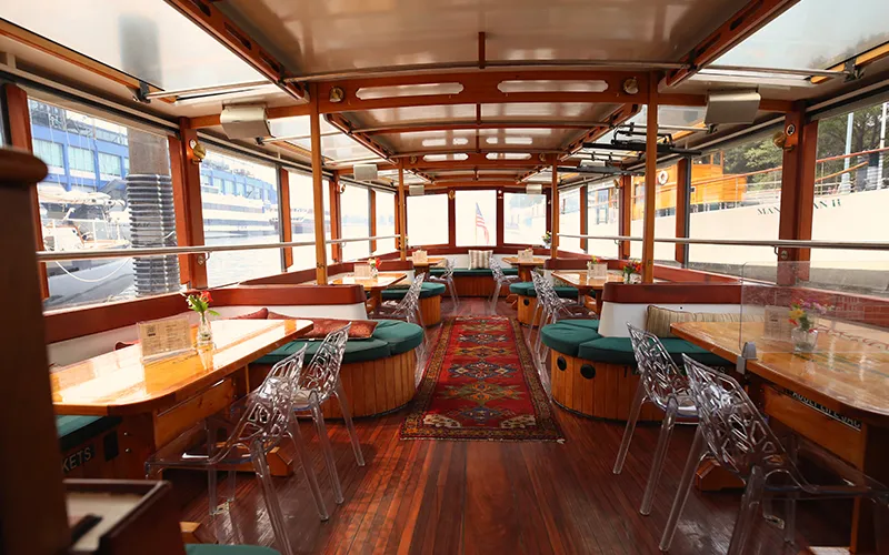 Grand Salon of yacht Manhattan showcasing the tables, chairs and windows.