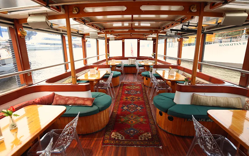 Grand Salon of yacht Manhattan showcasing the tables, chairs and windows.