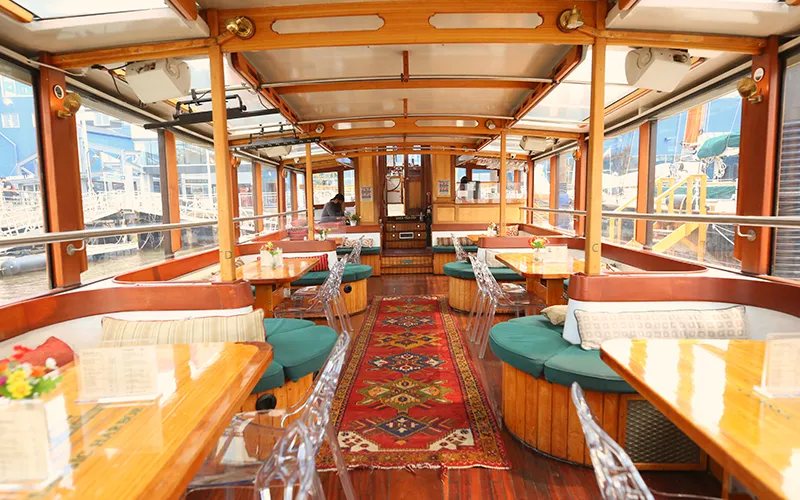 Grand Salon of yacht Manhattan showcasing the tables, chairs and windows.