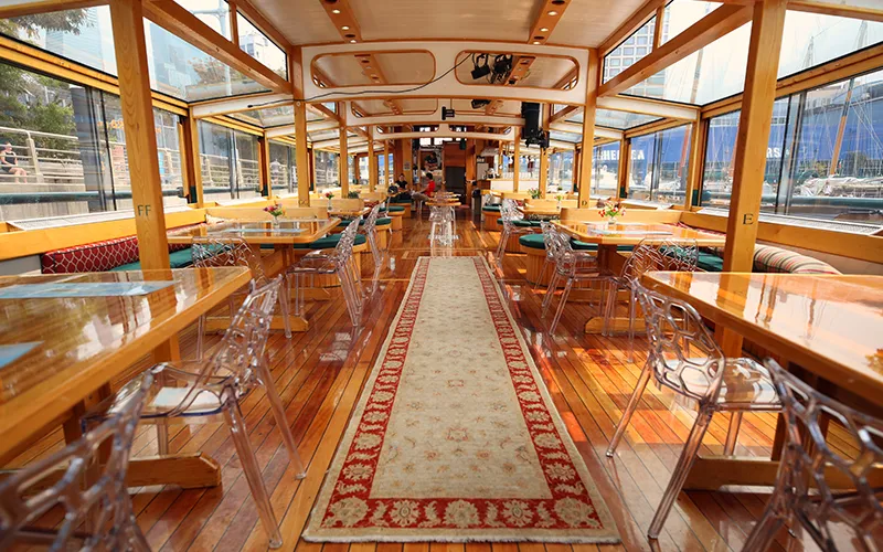 The grand salon of the yacht Manhattan II showcasing the tables, chairs and windows.