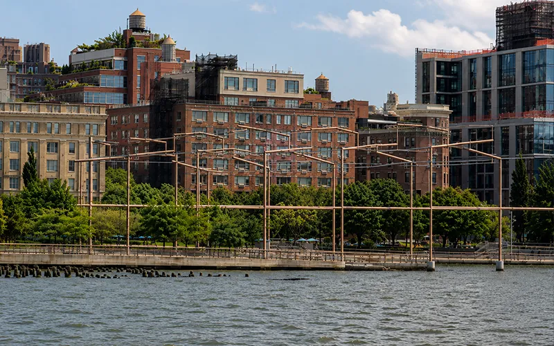 Unframed1 Metal frame of a building along the water on the Hudson River with the city skyline behind it