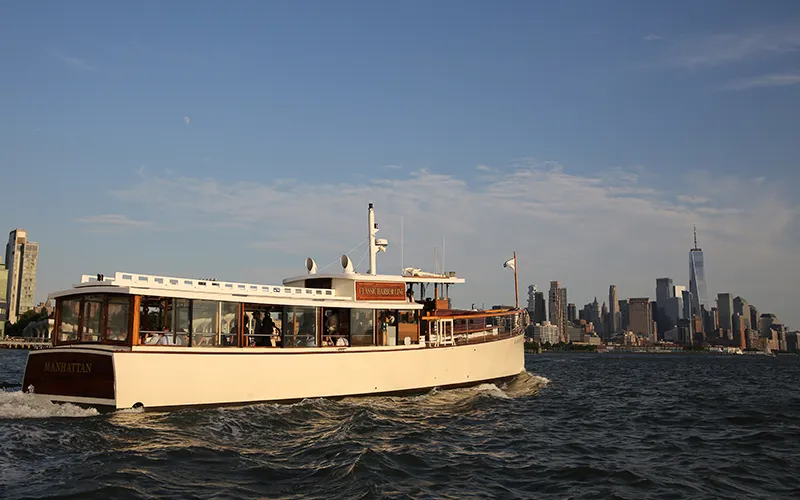 The Yacht Manhattan Cruising on the Hudson River at Sunset with the NYC skyline in the background