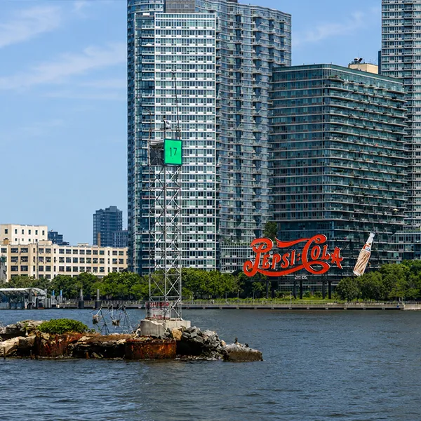 The Pepsi Cola sign and a nautical marker from the perspective of the water.